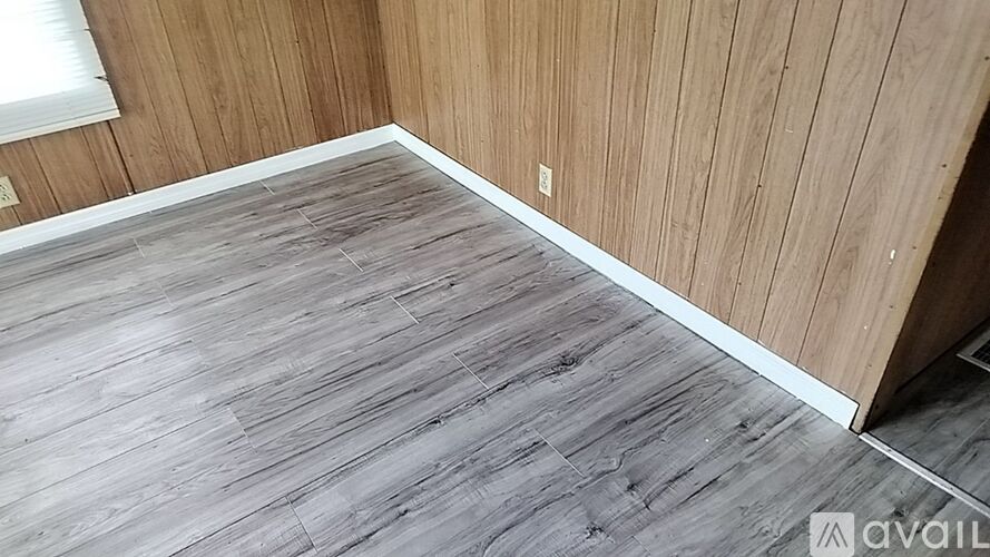 A room with wooden walls and a grey wooden floor.