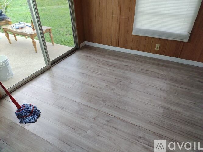 A room with a wooden floor and a mop.