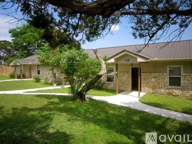 A house with a stone wall and a tree in front of it.