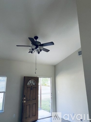 A ceiling fan in a room with a wooden door.