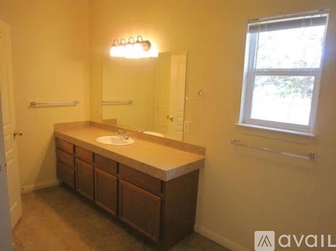 A bathroom with a sink, mirror, and a window.