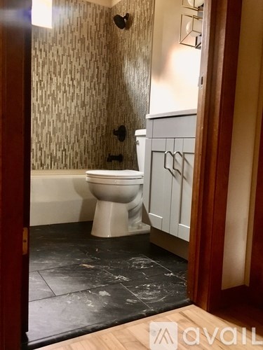 A white toilet in a bathroom with a wooden floor and a wallpapered wall.