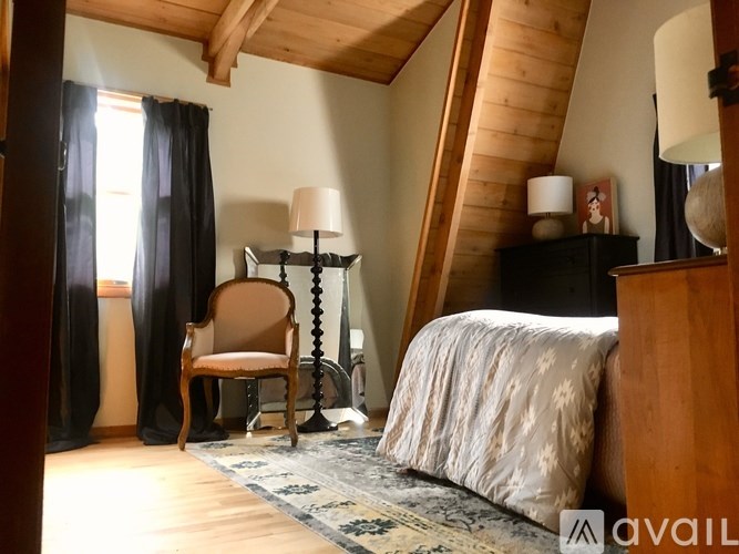 A bedroom with a bed, chair, and lamp.