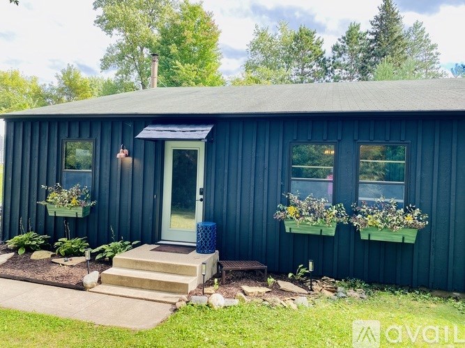 A blue house with a white door and windows, and a flower box on the right side.