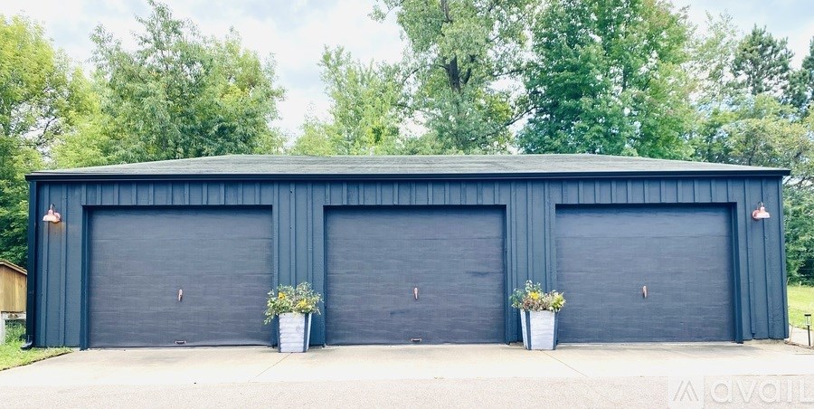 A large garage with two doors and two potted plants on either side.