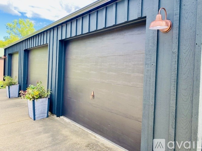 A grey garage door with a closed grey door and a pink light on the wall.