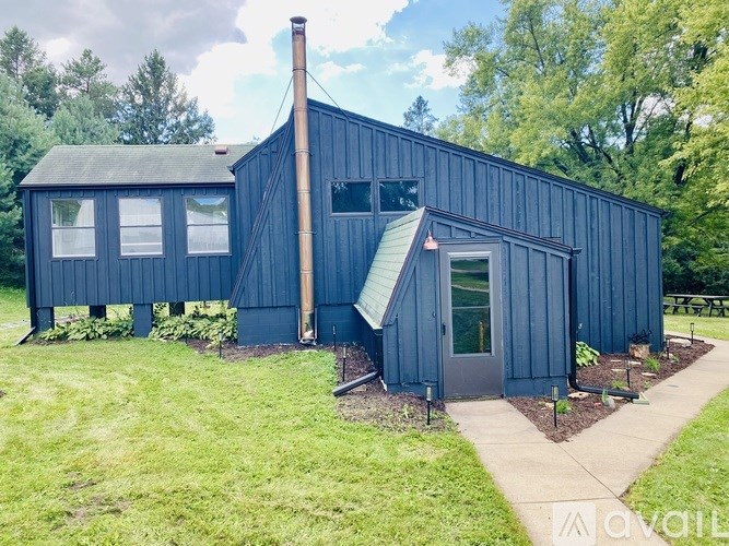 A blue wooden building with a grey roof and a chimney.