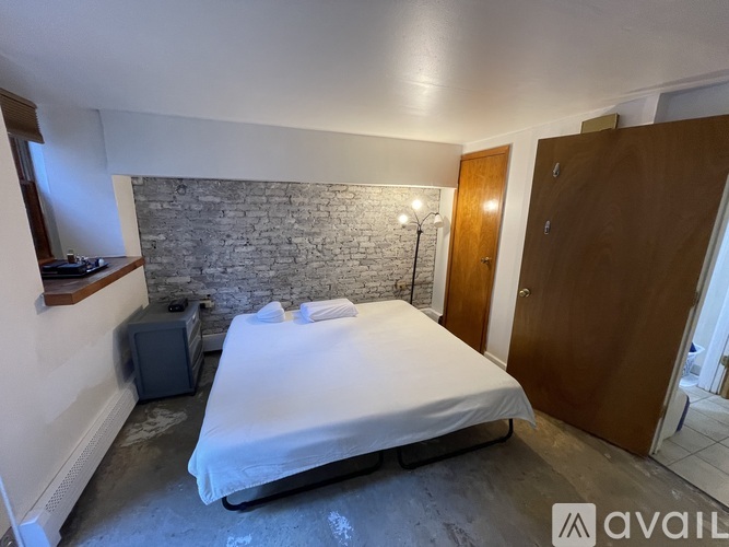 A bedroom with a bed, a speaker, and a stone wall.