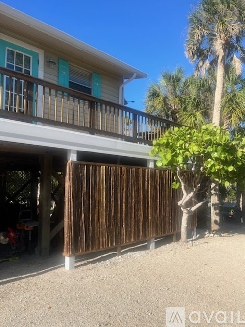 A wooden fence in front of a house with a tree in the background.