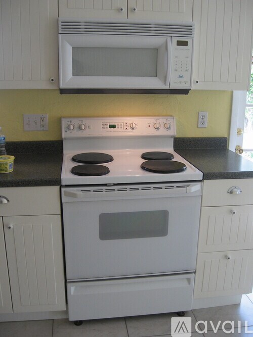 A white oven with a stove top sits under a microwave in a kitchen.