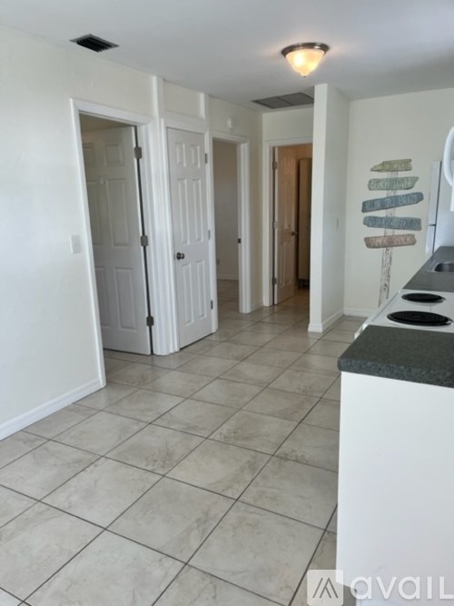 A kitchen with white cabinets and a black counter.