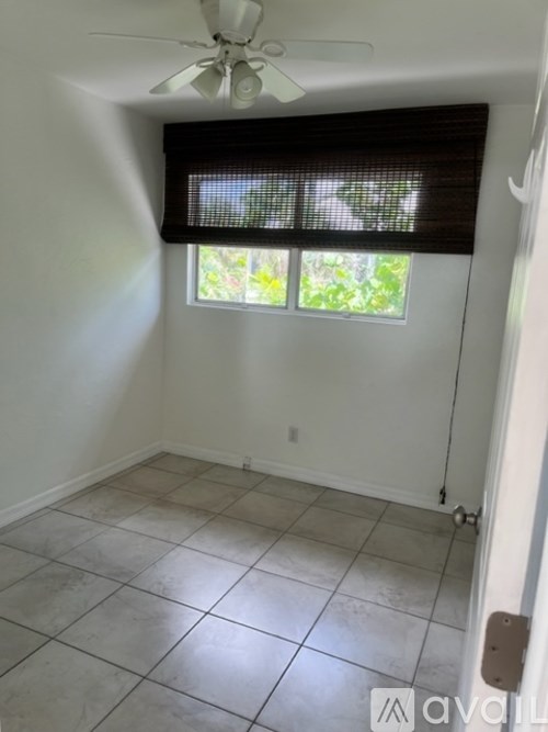 A room with a ceiling fan and a window with blinds.
