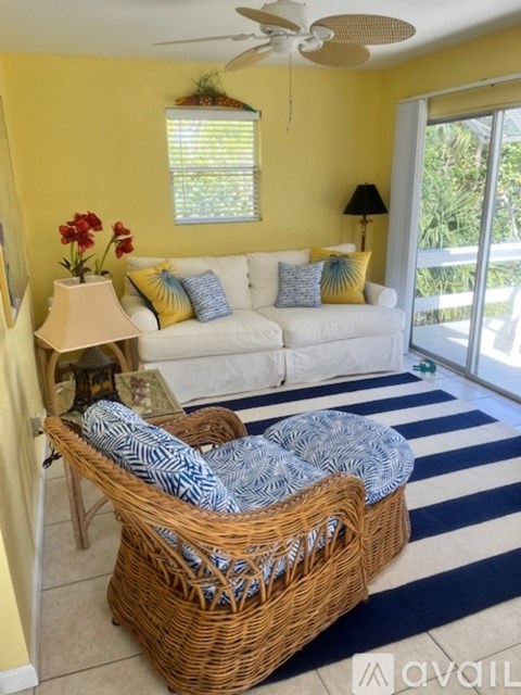 A living room with a white couch and a wicker chair.