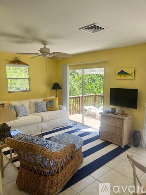A living room with a white couch and a wicker chair.