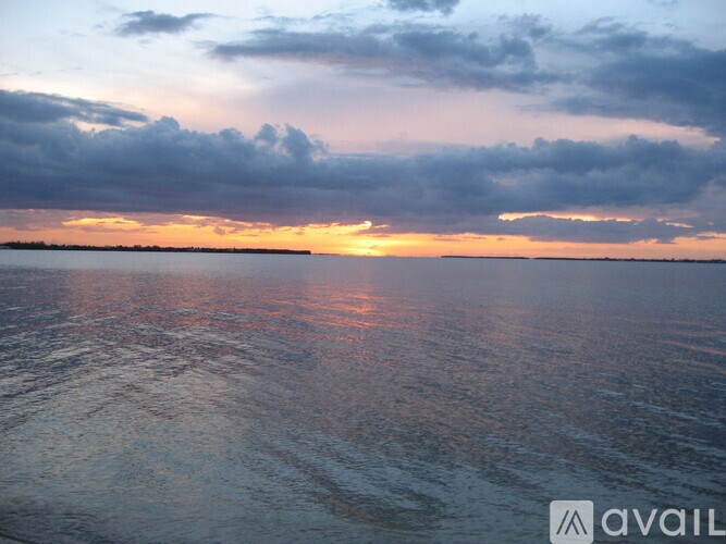 A sunset over the ocean with clouds reflecting in the water.