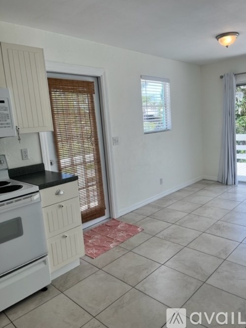A kitchen with white appliances and a tiled floor.