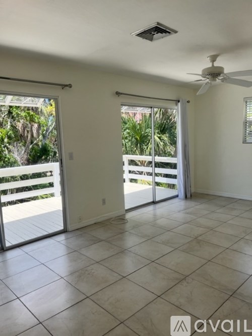 A room with a ceiling fan and sliding glass doors.