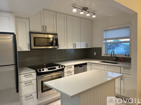 A kitchen with white cabinets and a black refrigerator.