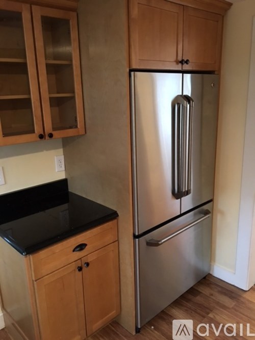A kitchen with a black countertop and a stainless steel refrigerator.