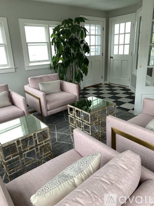 A living room with a glass coffee table and pink chairs.