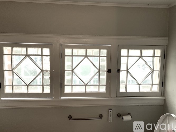 Three windows with white frames and diamond-shaped glass panes.