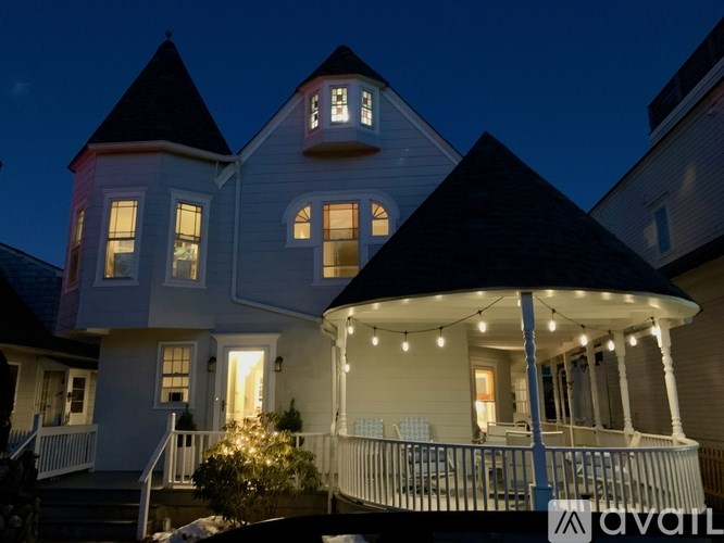 A house with a porch and lights strung up on the railing.