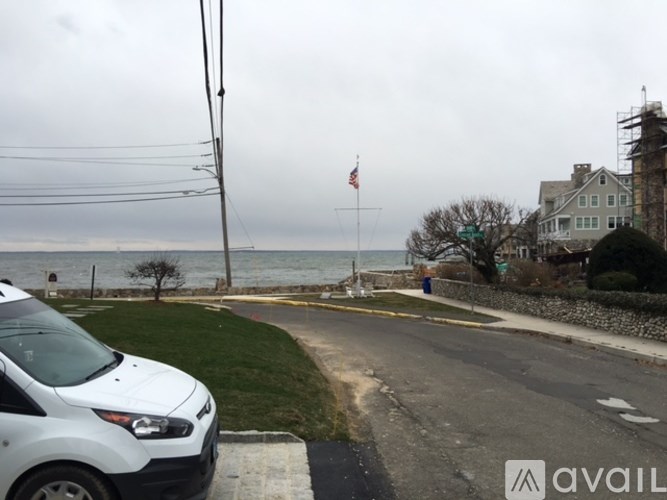 A white car is parked on the side of a road near a grassy area.