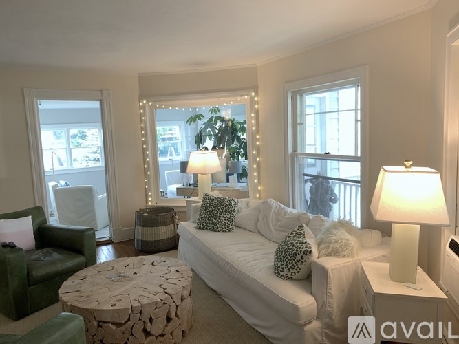 A living room with a white couch, a green chair, and a round table with a white base.