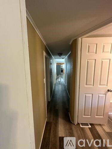 A hallway with a white door on the right and a light at the end.