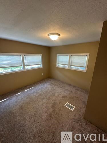A carpeted room with a window and a light on the ceiling.