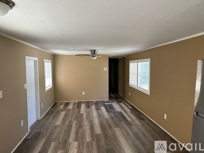 A room with a ceiling fan and wooden flooring.