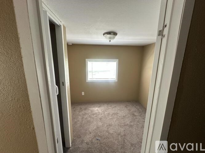 A room with a carpeted floor and a window letting in natural light.