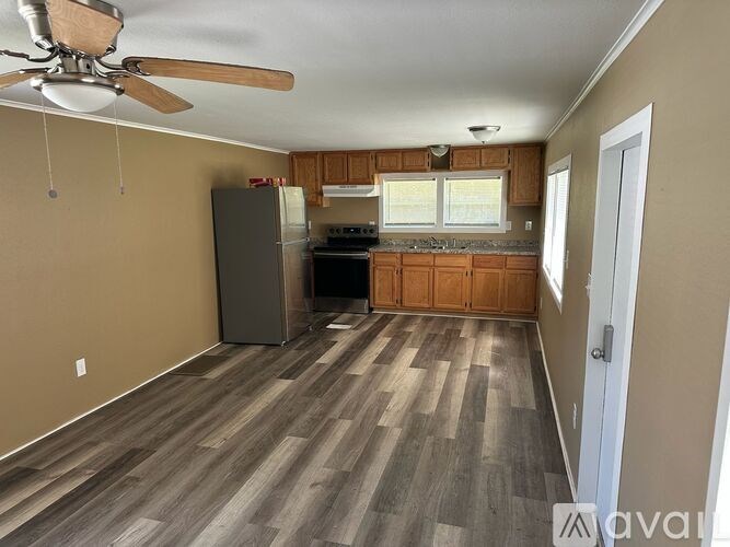 A room with a ceiling fan and wooden flooring.