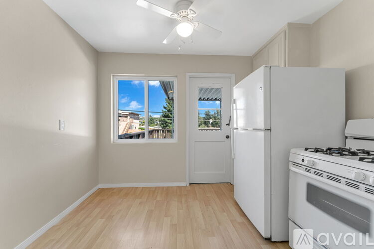 A kitchen with a white fridge and stove, a window with a view of the outside, and a ceiling fan.
