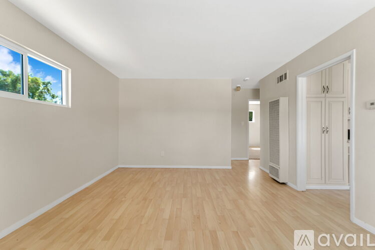 A spacious room with wooden flooring and white walls.