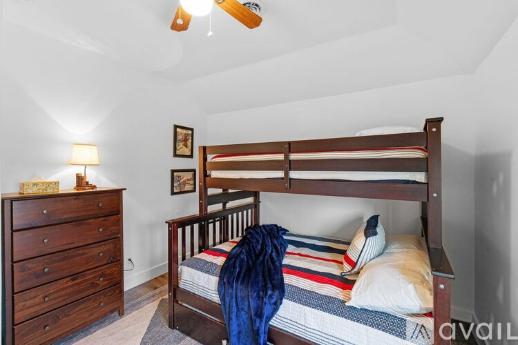 A black television is mounted on a white wall above a wooden staircase.