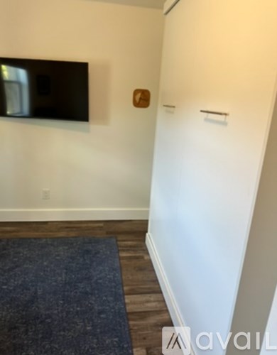 A room with a flat screen TV mounted on the wall and a dark rug on the floor.