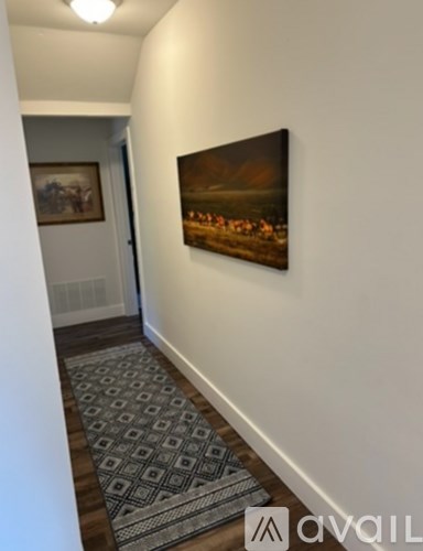 A hallway with a rug and a painting on the wall.