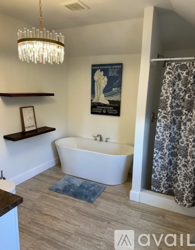A bathroom with a white bathtub and a chandelier hanging from the ceiling.