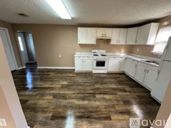 A kitchen with white appliances and wooden floors.