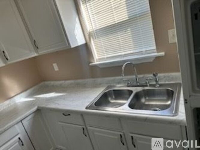 A kitchen with a double sink and white cabinets.