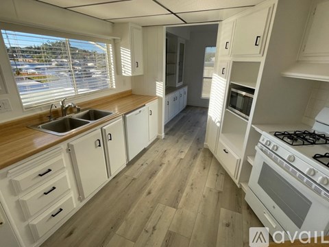 A kitchen with white cabinets and a wooden floor.