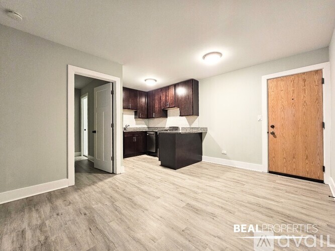 A spacious room with wooden flooring and a kitchen area with brown cabinets.