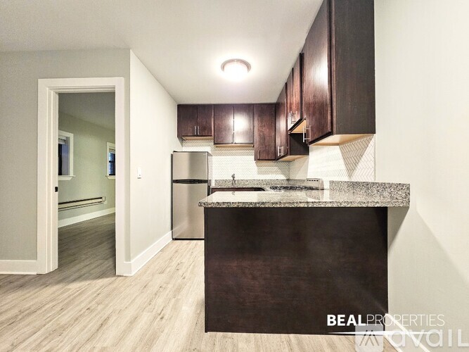 A kitchen with dark brown cabinets and a granite countertop.