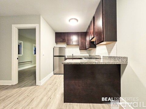 A kitchen with dark brown cabinets and a granite countertop.