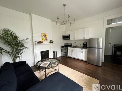 A living room with a fireplace and a dining area in the background.