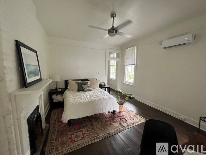 A bedroom with a bed, a fireplace, and a ceiling fan.