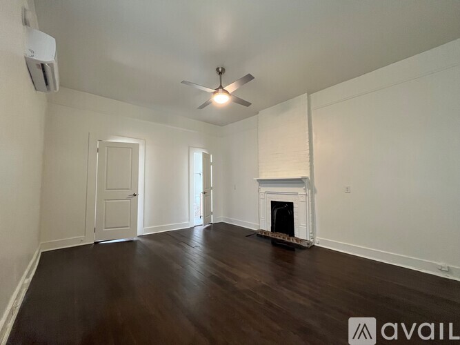 A spacious room with a fireplace and a ceiling fan.