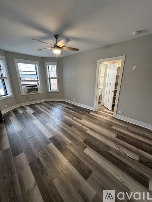 A room with a ceiling fan and wooden flooring.