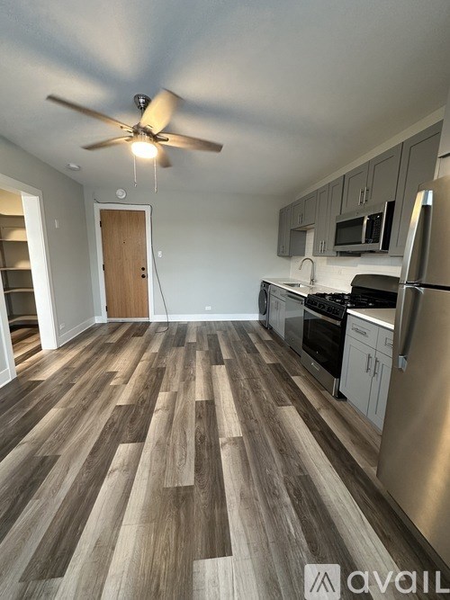 A kitchen with a fan on the ceiling and wooden flooring.